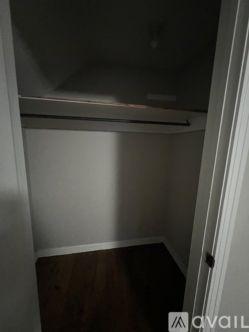 A small, empty room with a wooden floor and white walls.