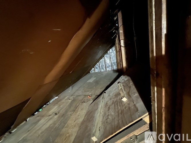 A dark, narrow space with a wooden floor and a metal beam overhead.