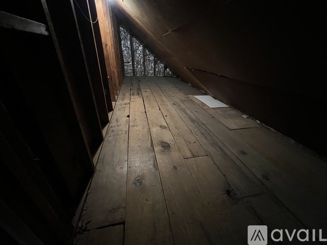 A long wooden hallway with a light at the end.
