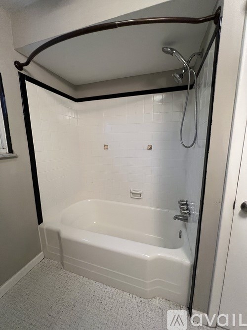 A white bathtub with a shower head and a black frame.