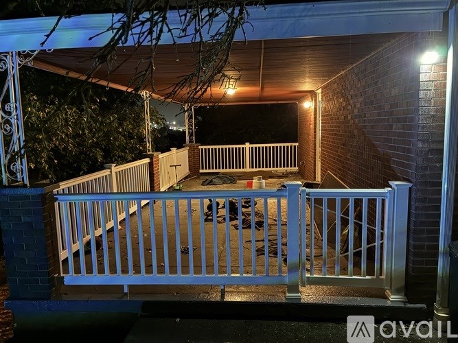 A patio with a white railing and a brick wall.