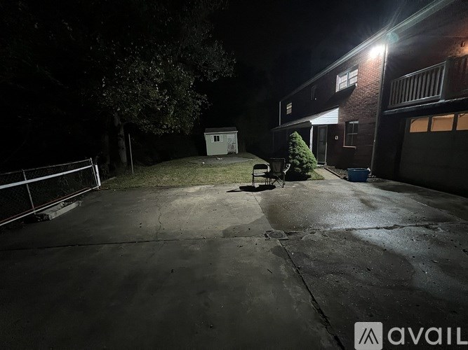 A red car is parked on a wet driveway at night.