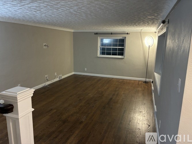 A room with wooden flooring and a window with a white frame.
