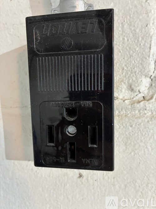 A black electrical outlet box mounted on a white wall.