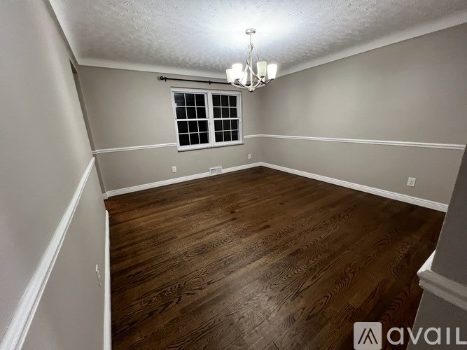 A room with wooden flooring and a chandelier.
