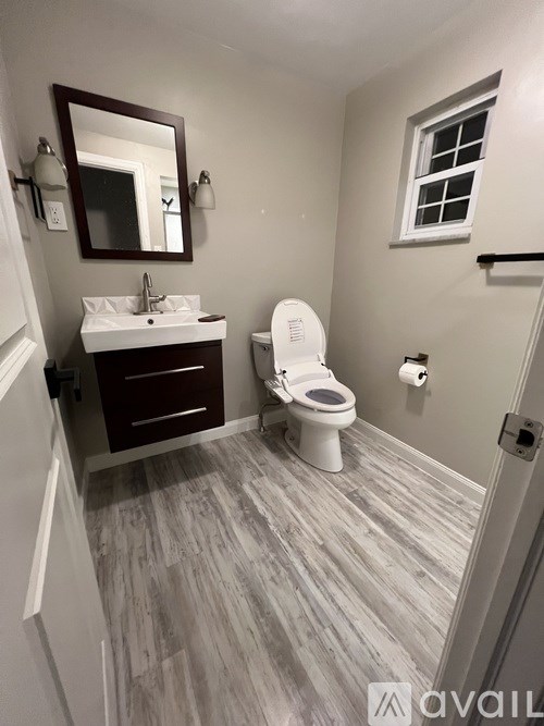 A bathroom with a toilet, sink, and mirror.