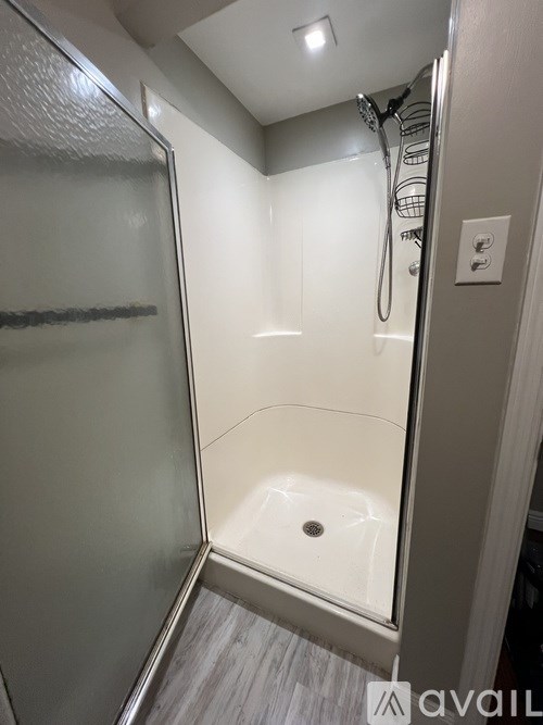 A shower area with a glass door and a white shower head.