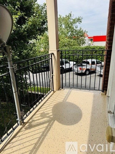 A balcony with a black railing and a satellite dish on the left.