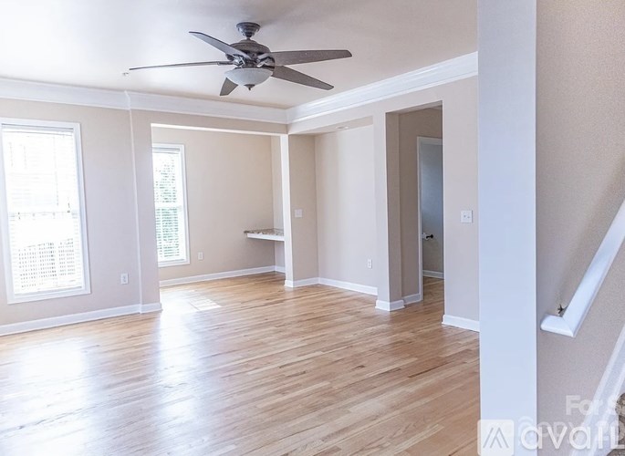 A room with a ceiling fan and wooden flooring.