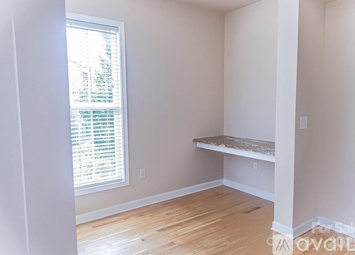 A room with a window and a bench under a sign that says "For Sale".