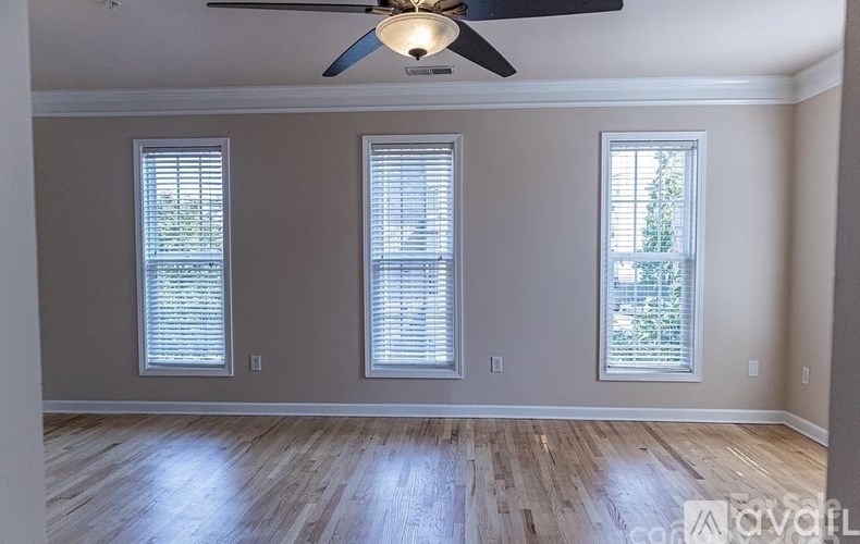 A room with wooden floors and three windows.