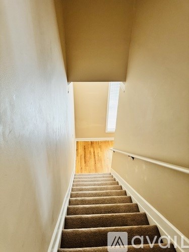 A staircase with a beige carpeted runner and white walls.