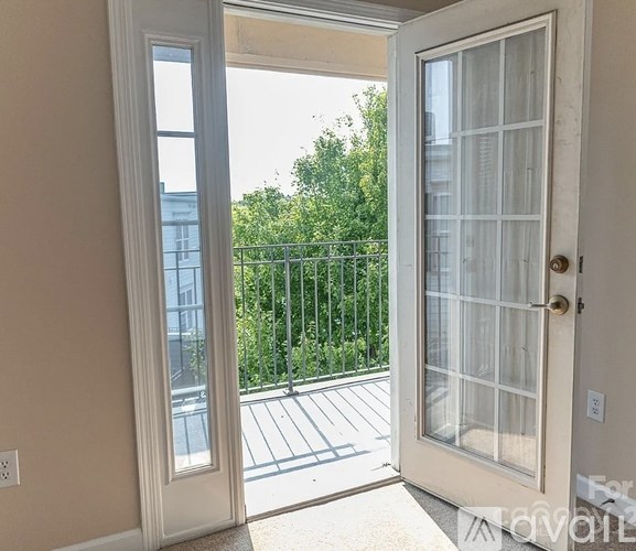 A white door with a glass window is open to a balcony with a metal railing.