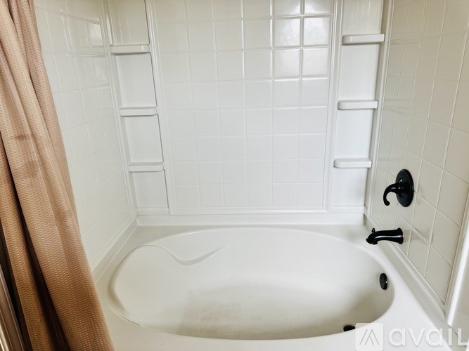A white bathtub with a black faucet and a brown shower curtain.