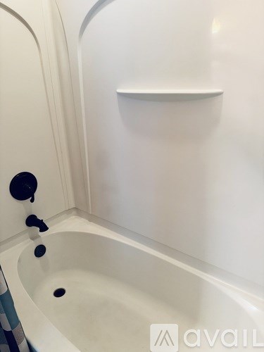 A white bathtub with a black faucet and a black drain.