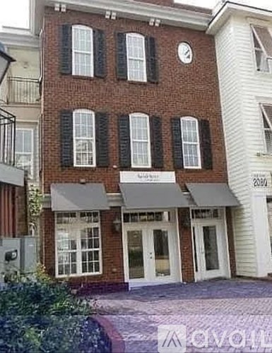 A brick building with a clock on the wall and awnings on the windows.