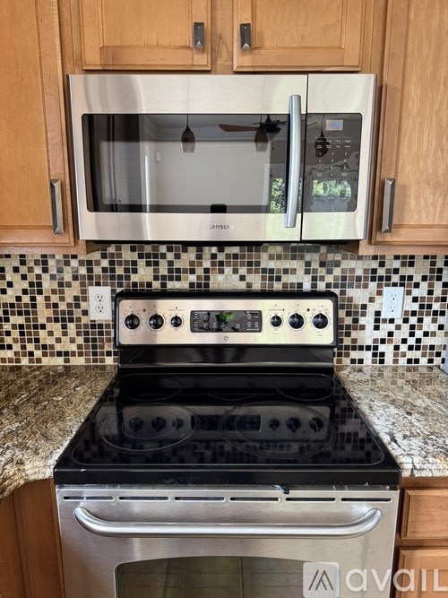 A kitchen with a black stove top oven and a silver microwave above it.