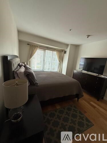 A bedroom with a bed, dresser, and television.