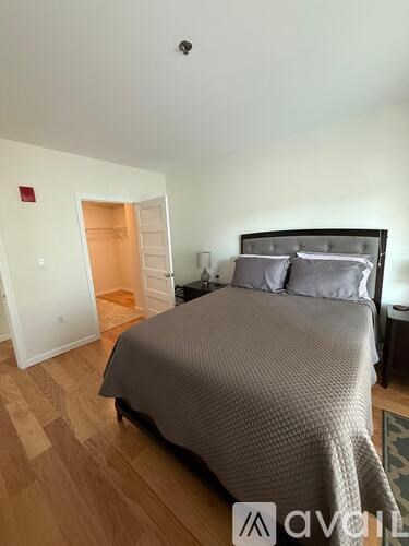A bedroom with a bed, nightstand, and a doorway leading to another room.