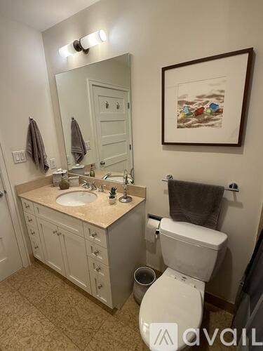 A bathroom with a toilet, sink, and mirror.