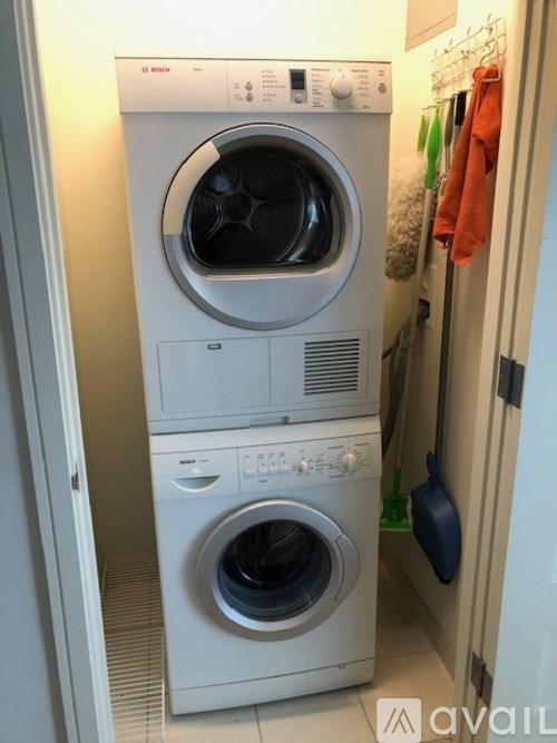 A white front loading washing machine with a dryer on top is in a laundry room.