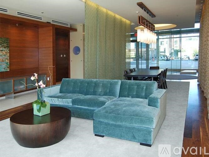 A living room with a green velvet couch and a coffee table with a vase of flowers on it.