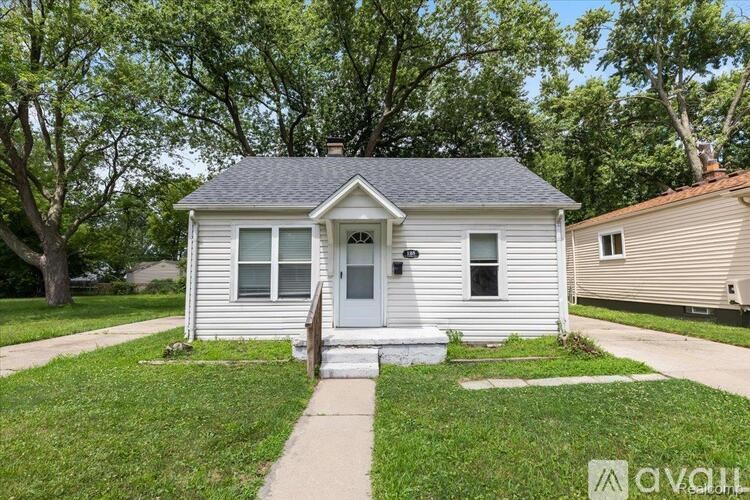 A small white house with a grey roof and a front porch.