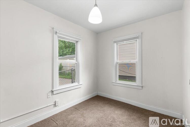 A room with two windows, one of which has blinds.
