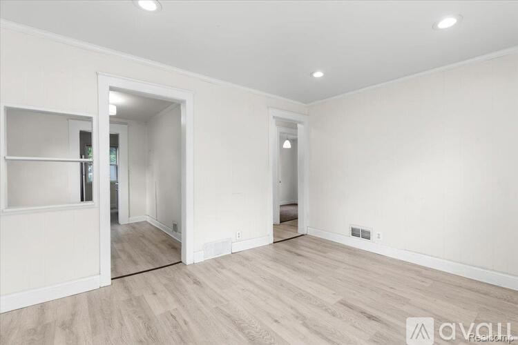 A spacious room with wooden flooring and white walls.