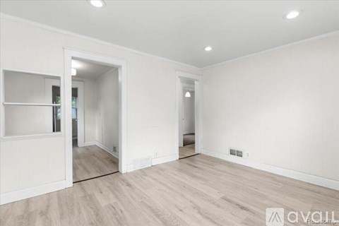 A spacious room with wooden flooring and white walls.