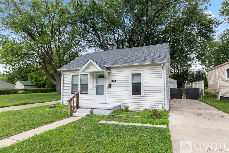A small white house with a front porch and a driveway.