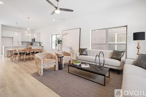 A modern living room with a white sofa, a glass coffee table, and a large abstract painting on the wall.