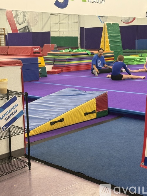 A gymnastics academy with a purple mat and a sign that says sanitation station.