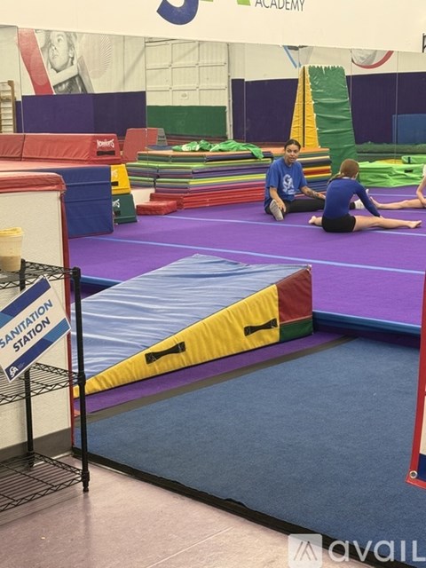 A gymnastics academy with a purple mat and a sign that says sanitation station.