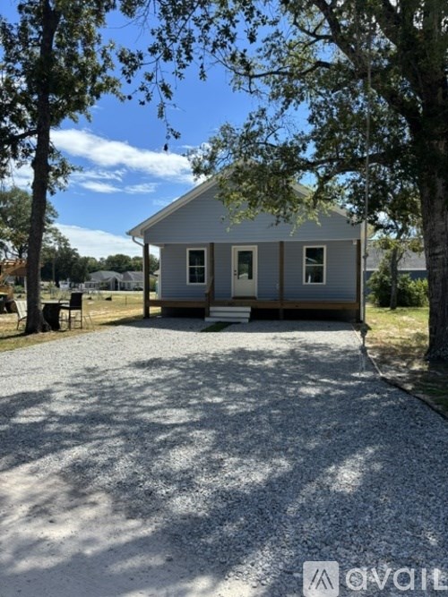 A small house with a gravel driveway in front.