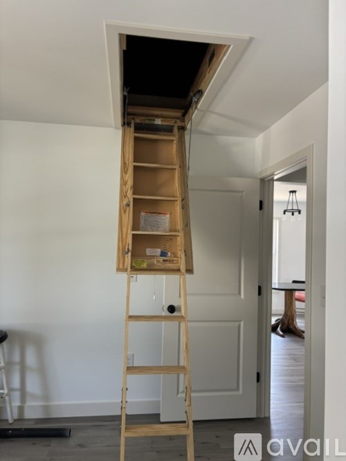 A wooden ladder is leaning against a white wall.