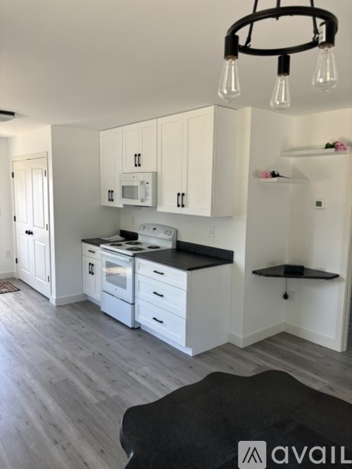 A kitchen with white cabinets and black countertops.