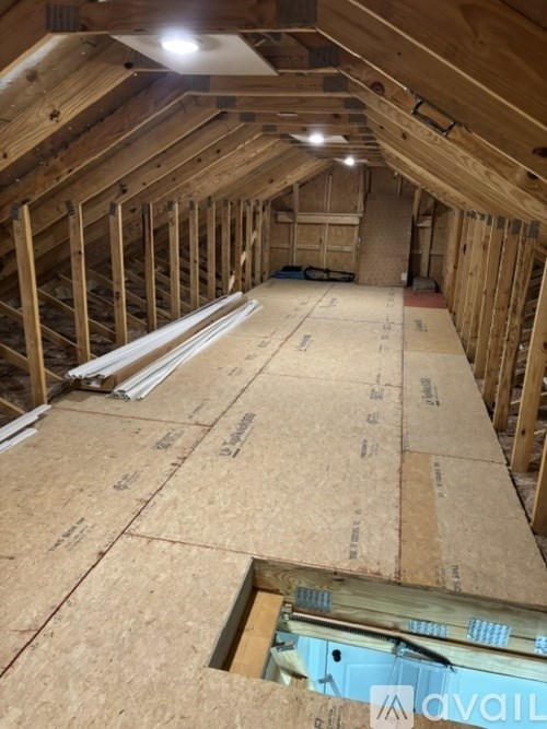 A view of an attic under construction with wooden beams and insulation.