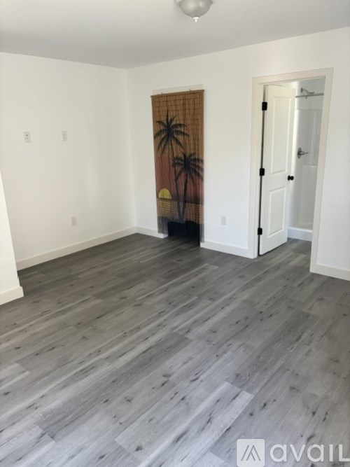 A room with wooden flooring and a doorway leading to another room.