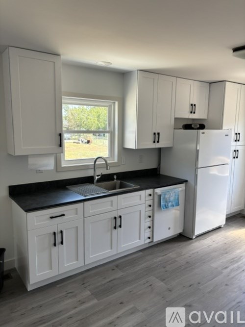 A kitchen with white cabinets and a black countertop.