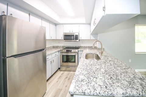 A kitchen with a granite counter top and stainless steel appliances.