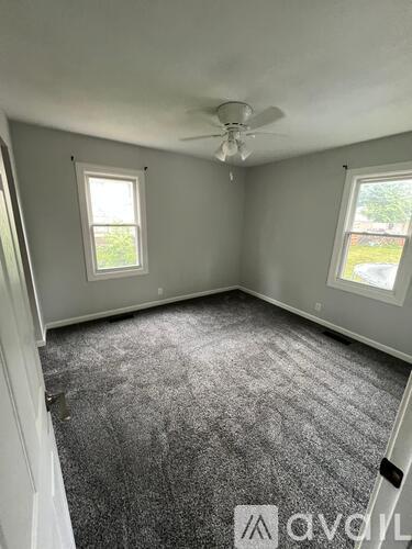A room with grey carpet and a ceiling fan.