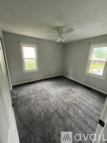 A room with grey carpet and a ceiling fan.