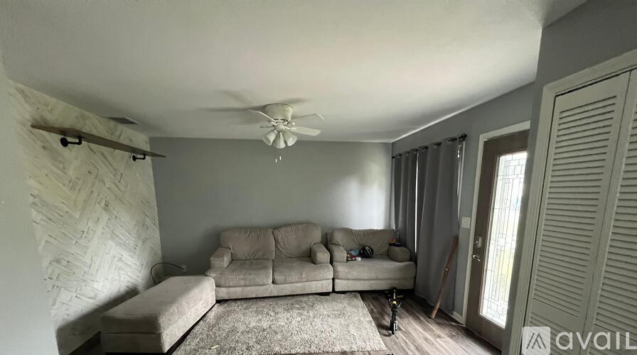 A living room with a couch, a rug, and a ceiling fan.