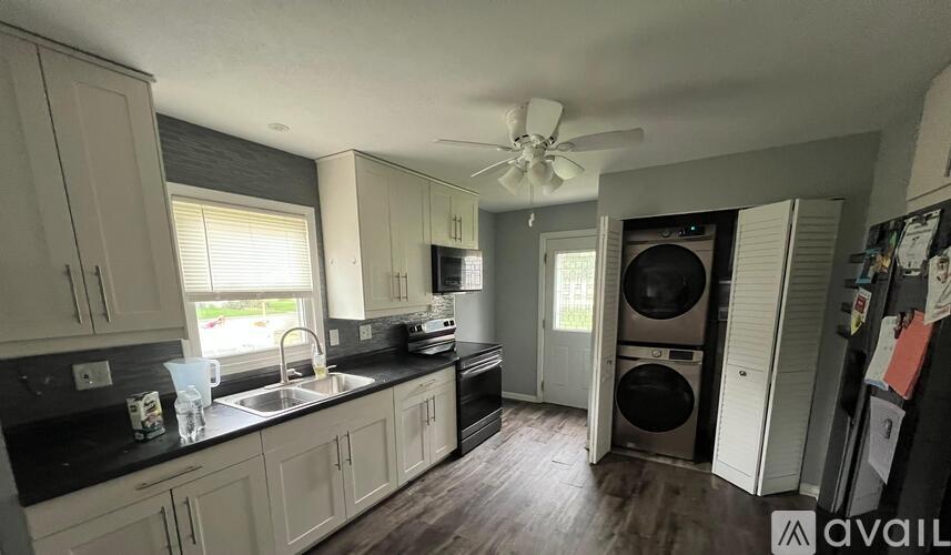 A kitchen with white cabinets and a black countertop.