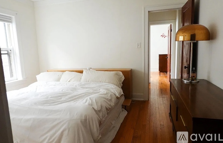A bedroom with a large bed and a wooden floor.