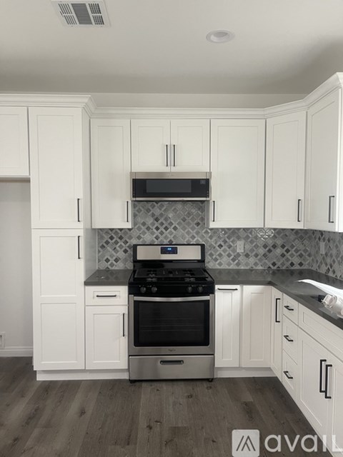 A kitchen with white cabinets and a black stove top.