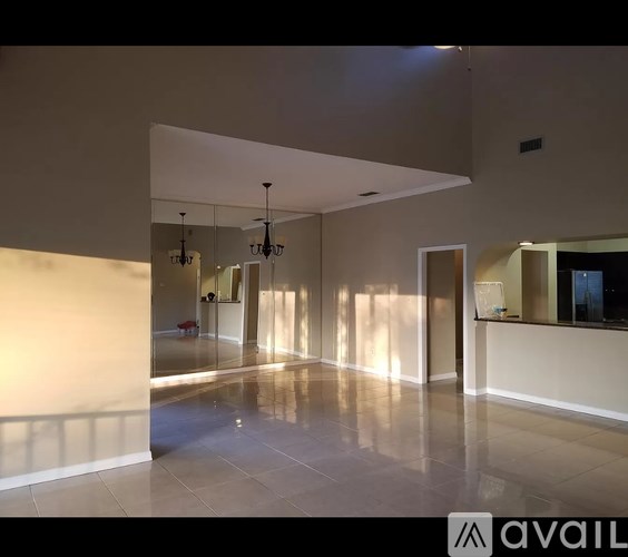 A spacious room with a tiled floor and a large mirror on the wall.