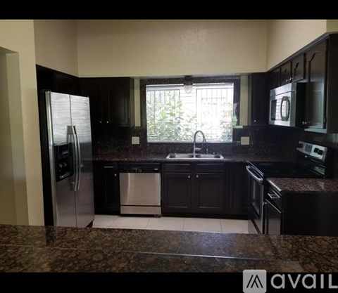 A kitchen with black cabinets and a granite countertop.