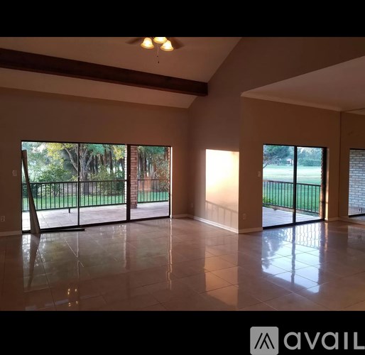 A spacious room with a view of a green lawn through the windows.